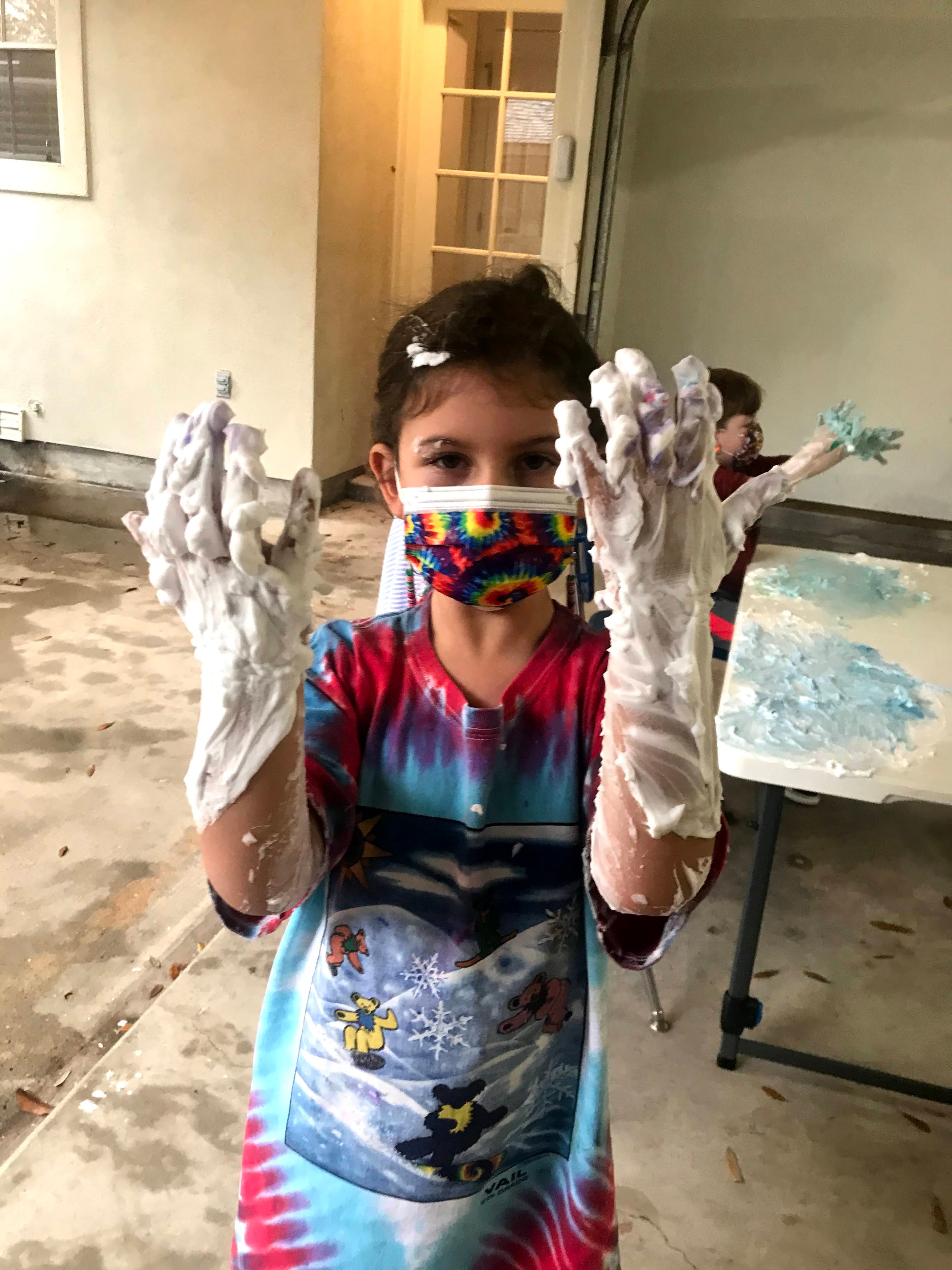 Child covered in shaving cream doing art