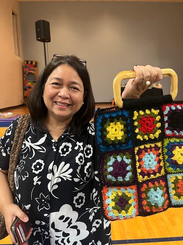 Student proudly showing off her colorful crocheted granny square bag