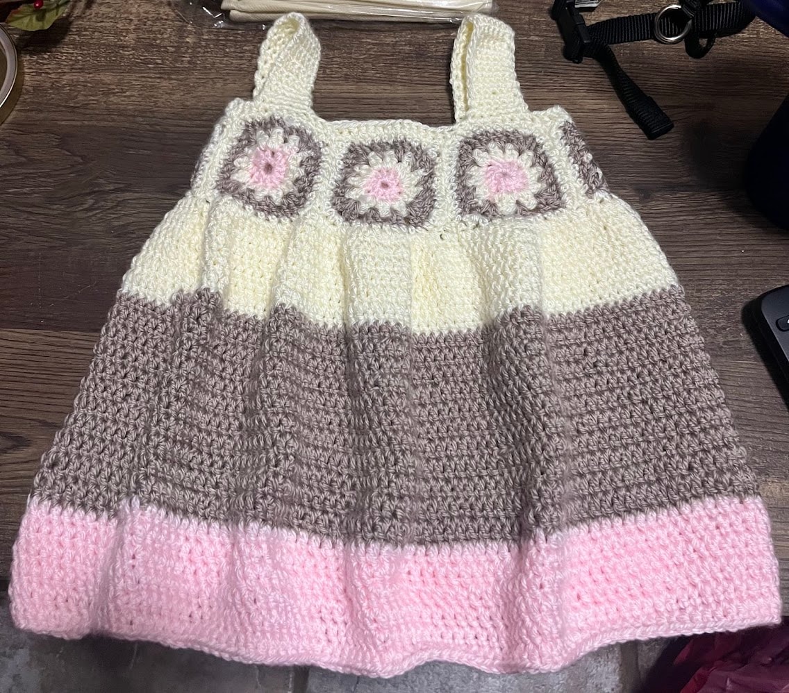 Handmade crocheted baby dress in cream, gray, and pink