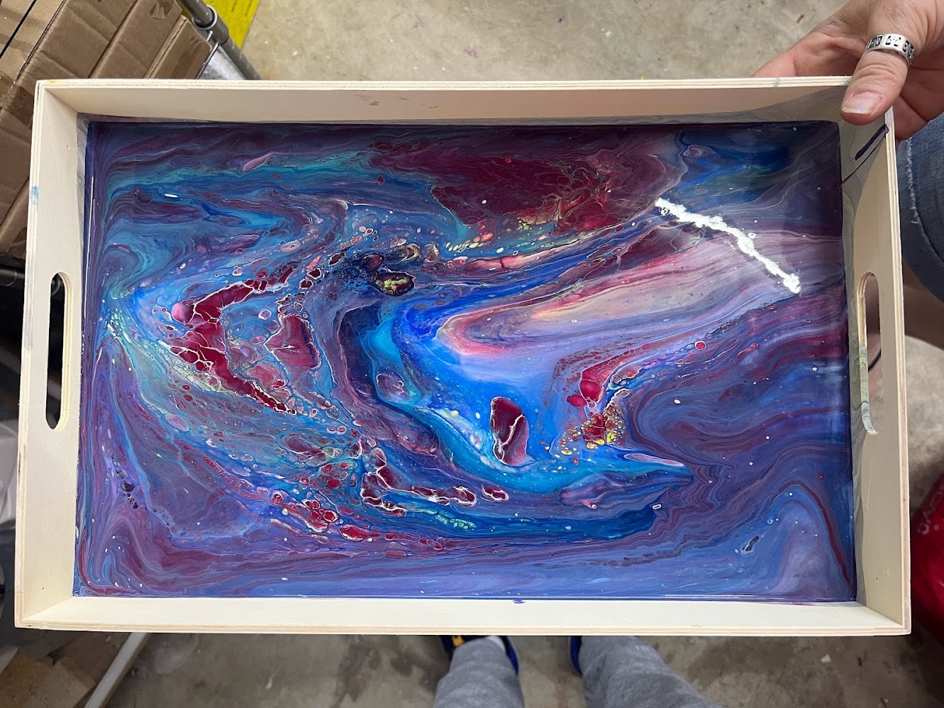 Vibrant blue and red marbled fluid art on a wooden tray
